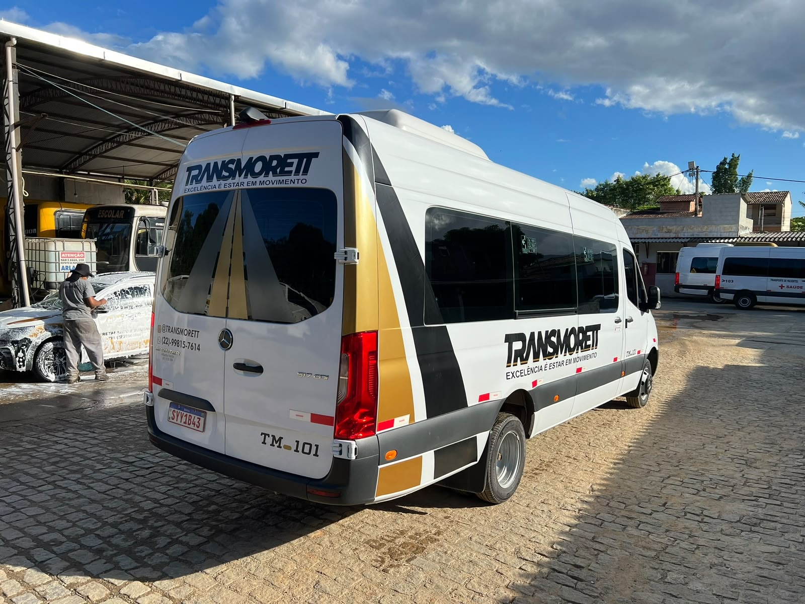 Van executiva Transmorett em pátio operacional, com outras vans da frota ao fundo